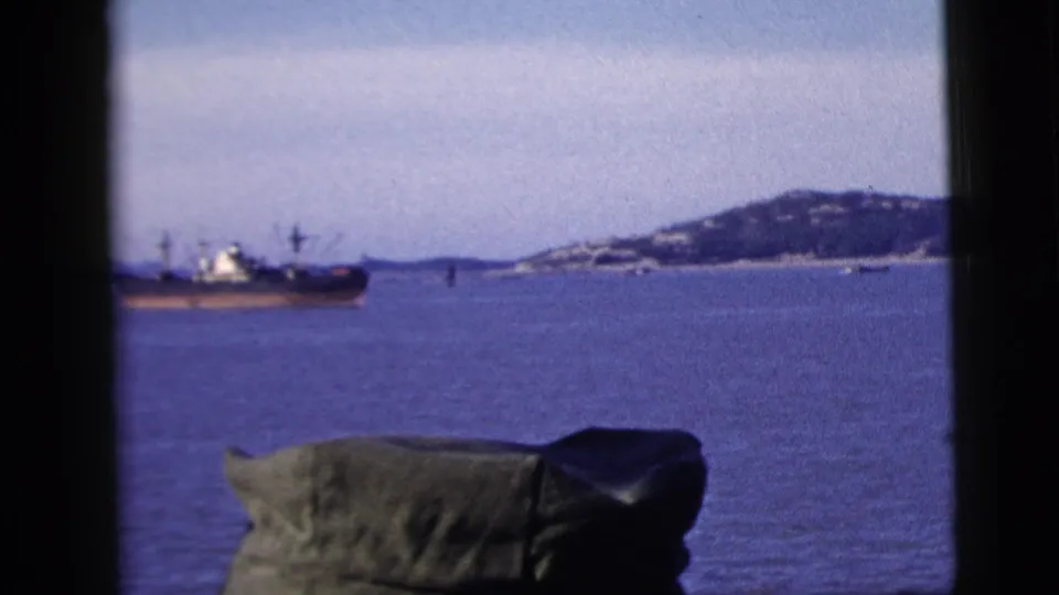 The bay view shows a large ship, distant hillside, and foreground green hat in 1958 New York City 8mm footage.