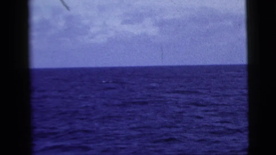 1958 8mm travel footage looking over open blue water and a level horizon, with dark frame edges and visible film texture.