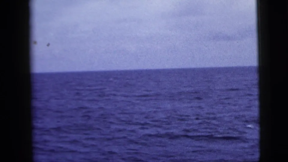 1958 8mm view of open ocean and a level horizon, seen through a dark central divider and side frame edges.
