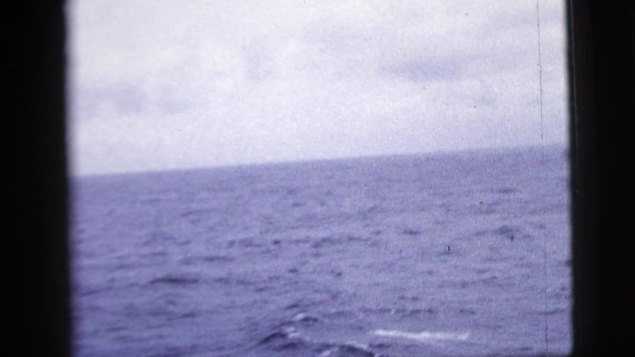 Calm ocean horizon with dark vertical window framing at the left and center.