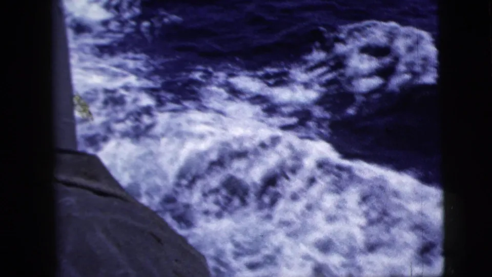 1958 home-movie frame showing foamy wake and darker open water beside the ship window edge.