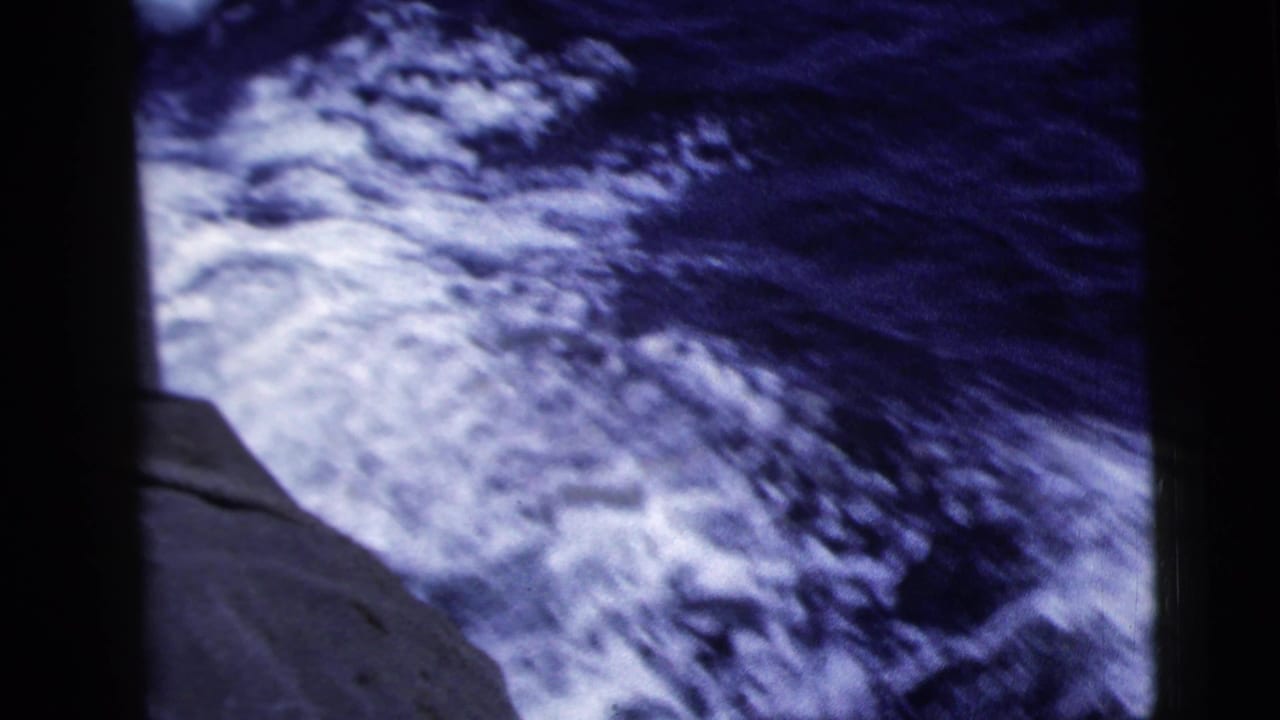 Rough blue water and white wake seen beside the edge of a moving boat.