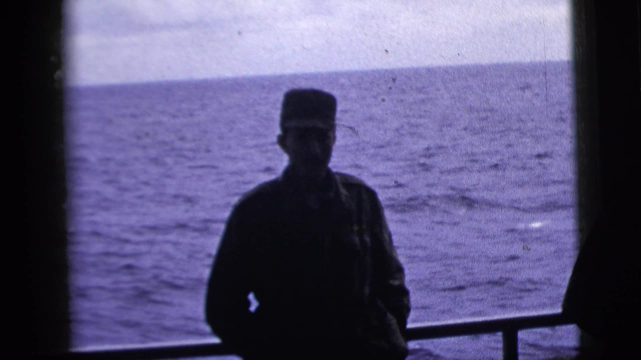 The adult man remains silhouetted on the boat deck, framed by railing and open ocean in the 1958 New York City clip metadata context.