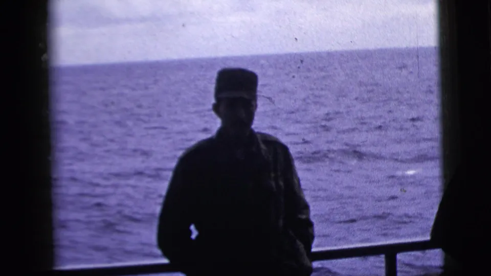 The adult man remains silhouetted on the boat deck, framed by railing and open ocean in the 1958 New York City clip metadata context.