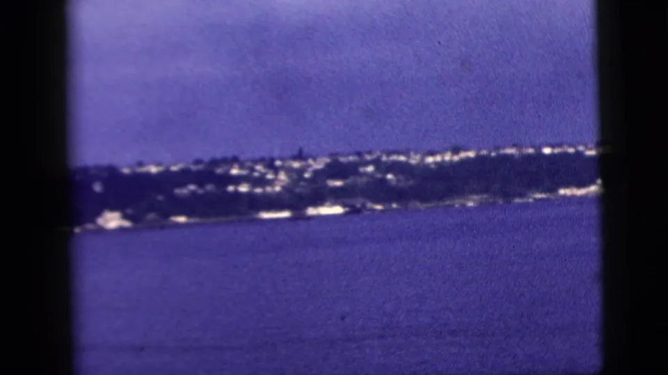 The final frame shows a distant coast and bright low buildings across the water, consistent with the clip's New York City 1958 travel metadata.