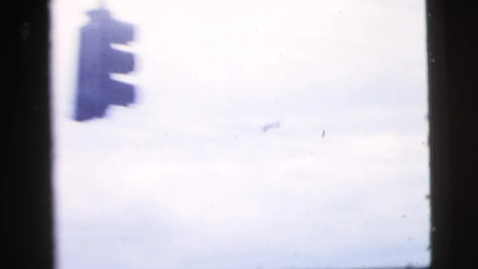 A traffic signal hangs against a bright city sky in this 1958 New York City home-movie frame.
