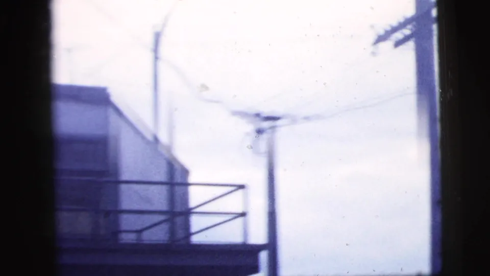 1958 New York City frame with building edge, railing, utility pole, and wires seen from a handheld window view.