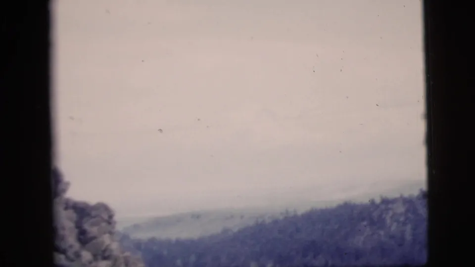 The final 1958 8mm frame shows a muted mountain ridgeline and overcast sky, with dark window edges enclosing the view.