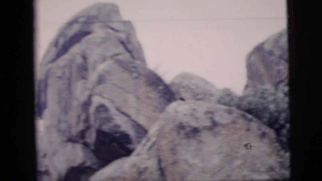 1958 New York City-labeled 8mm frame showing large weathered boulders and rocky outcrops in soft color.