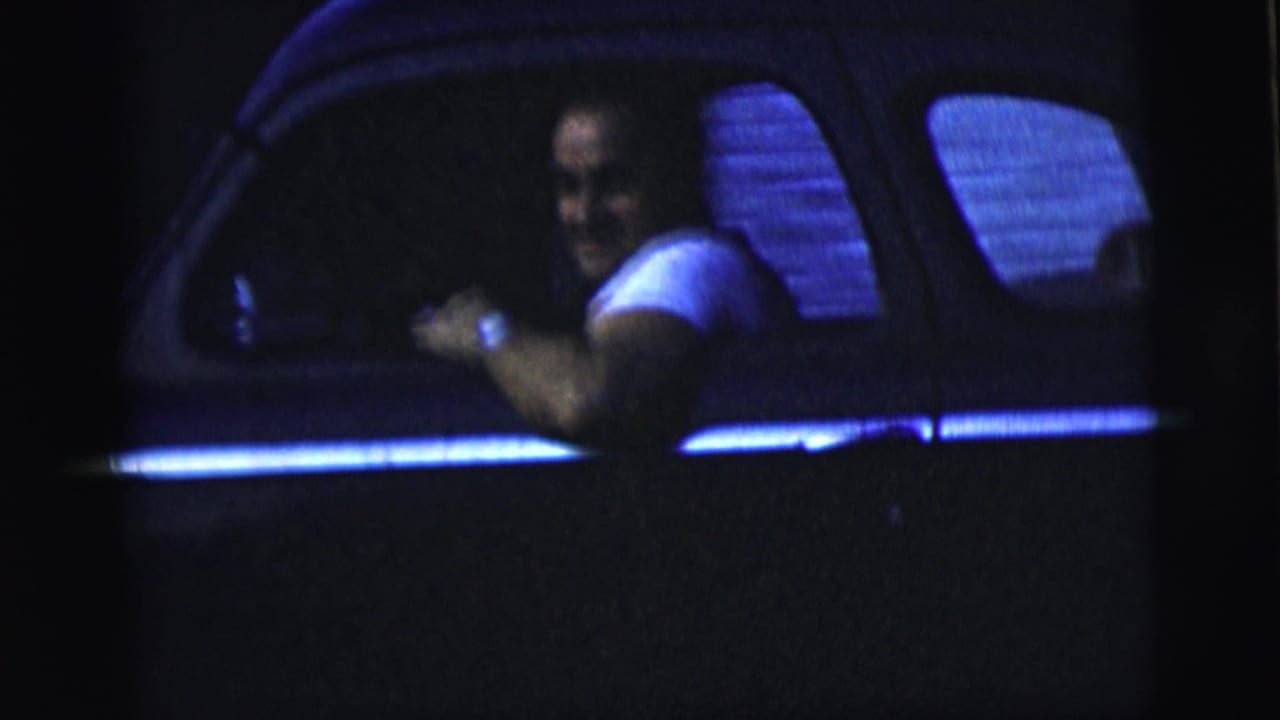Smiling man sits behind the wheel with his arm near the open window.