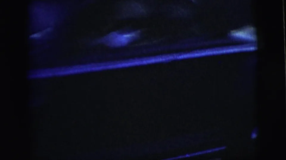 A close, soft 8mm view of the sedan side passes through blue night exposure, emphasizing motion and chrome reflections.