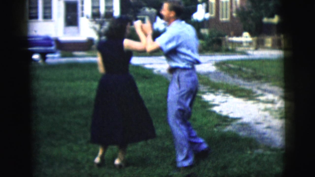 Young couple dances on a lawn near a house and walkway.
