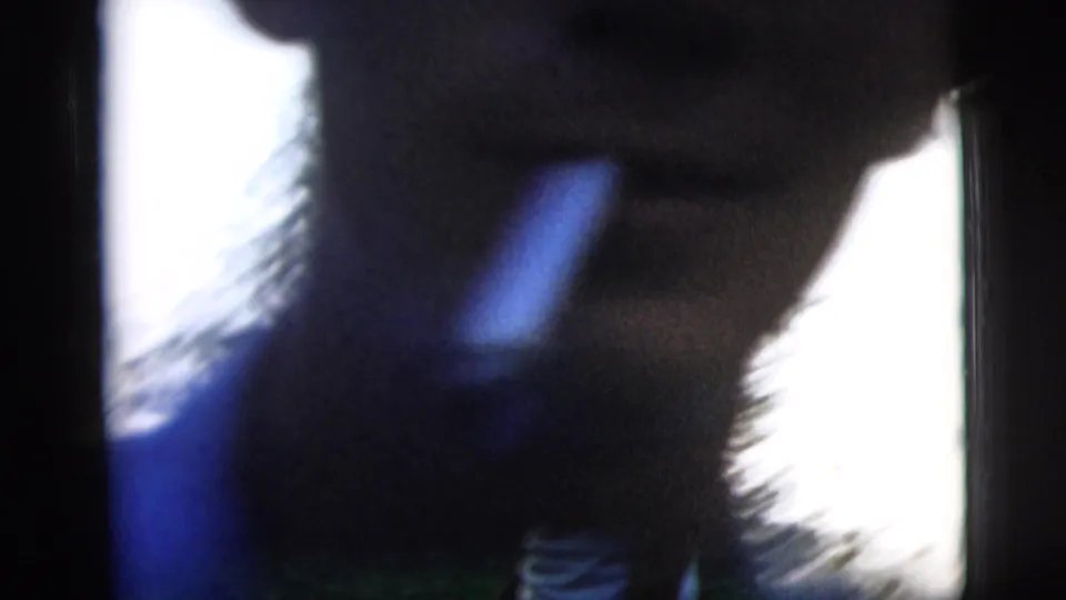 Soft, blurred 8mm frame of the man moving close to the camera, with bright outdoor light at the edge.