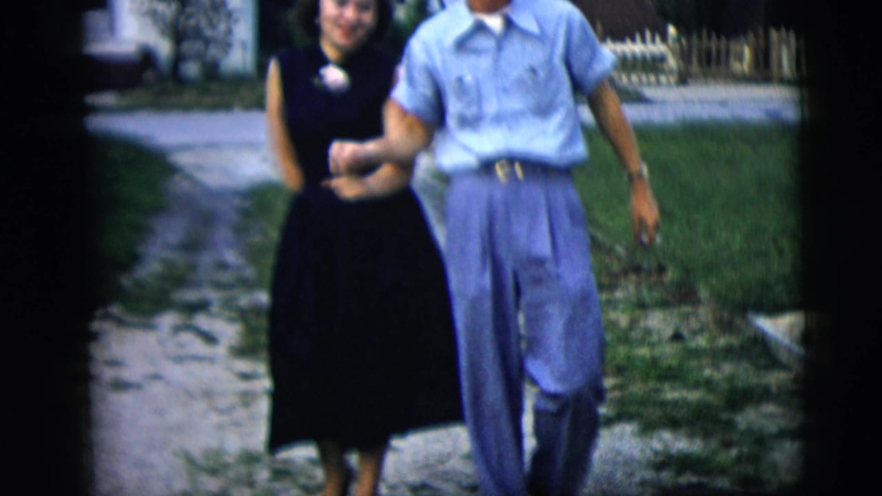 Young couple walking toward the camera along a residential driveway.