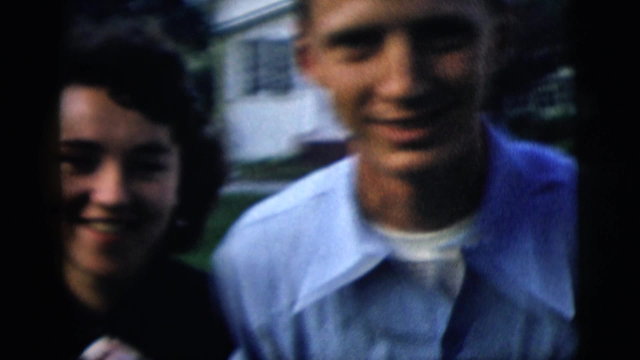 Young couple standing close outdoors in front of a suburban house.