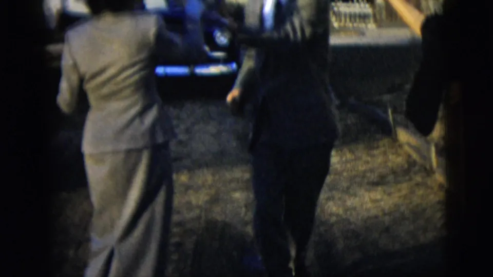 A brief outdoor frame shows people near a blue car, including a suited figure seen from behind, in 1958 New York City home-movie footage.