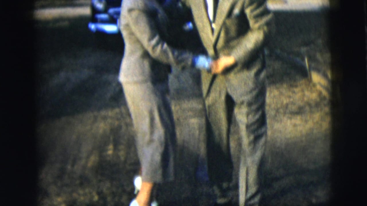 Close view of two suited adults dancing, with their bodies partly cropped by the frame.