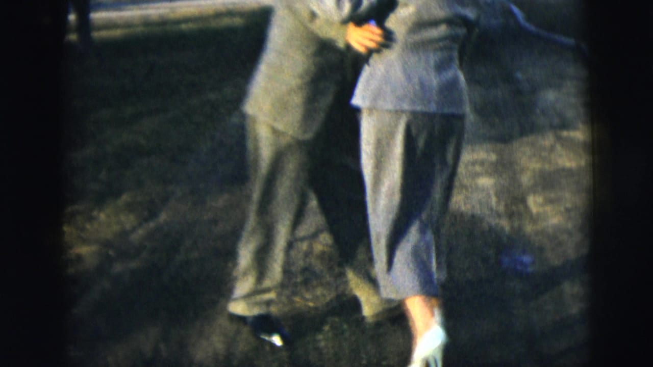 Couple in formal clothing dancing closely on a residential street.
