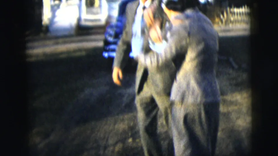 A man and woman continue their jive-like dance near a fence and house exterior in 1958 New York home-movie footage.