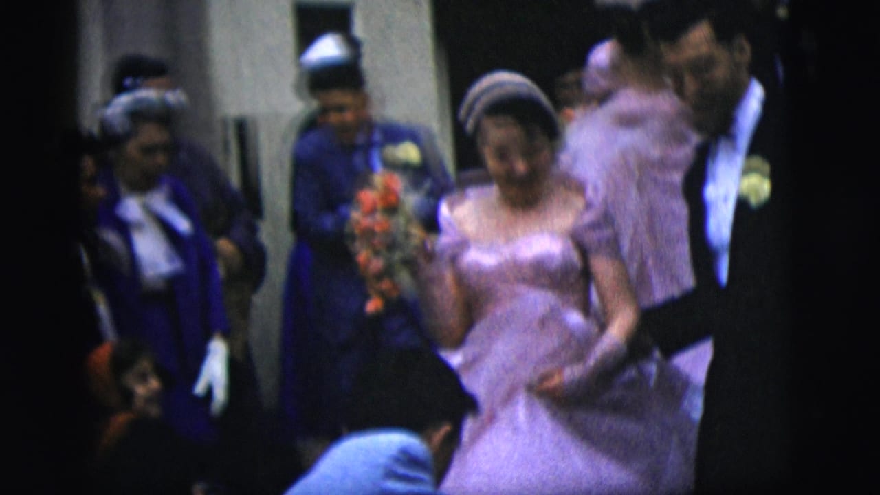 The bride, wearing a lavender gown and tiara, walks with the groom through guests in formal clothing in the New York City wedding scene.
