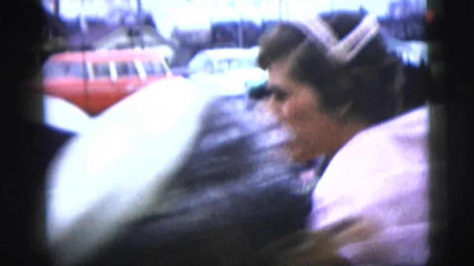 Outdoors, the bride appears near guests and parked mid-century cars, including a red station wagon, in the New York City wedding footage.