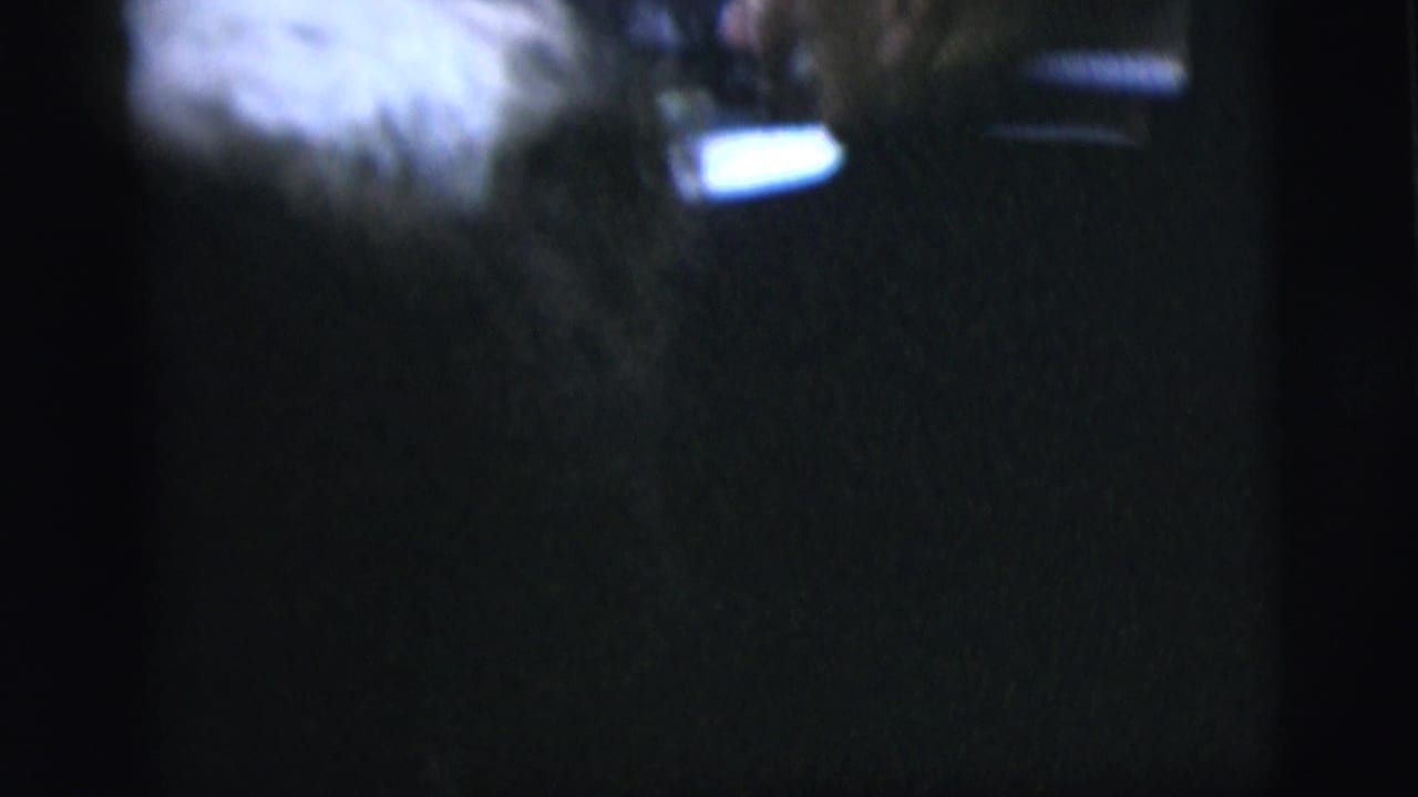 Very dark, soft frame with partial light areas and little identifiable detail.