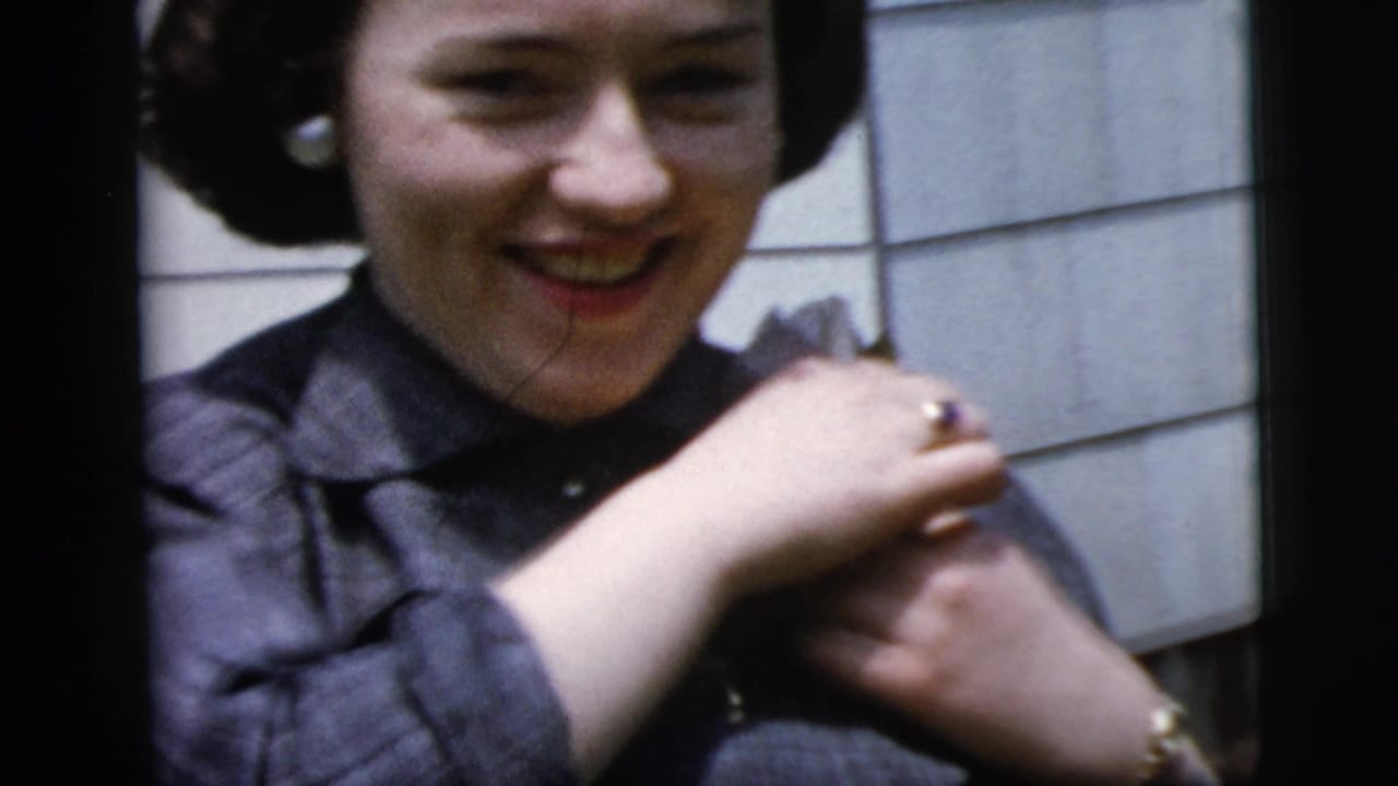 Woman smiling while lifting her hands near a corsage on her shoulder.
