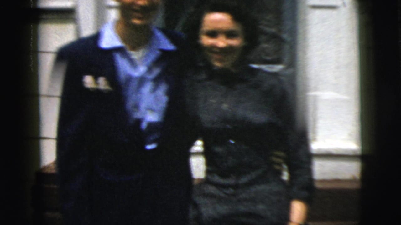 In 1958 New York City home-movie footage, a dressed-up couple stands close together outside a residential doorway.