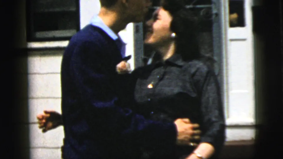 The couple embraces and kisses beside a residential doorway in the 1958 New York City home-movie footage.