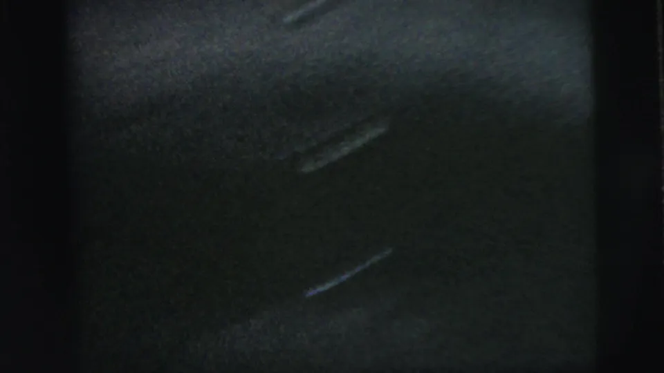 Soft, dark 8mm frame showing only a partial residential exterior and heavy contact-sheet border obstruction.