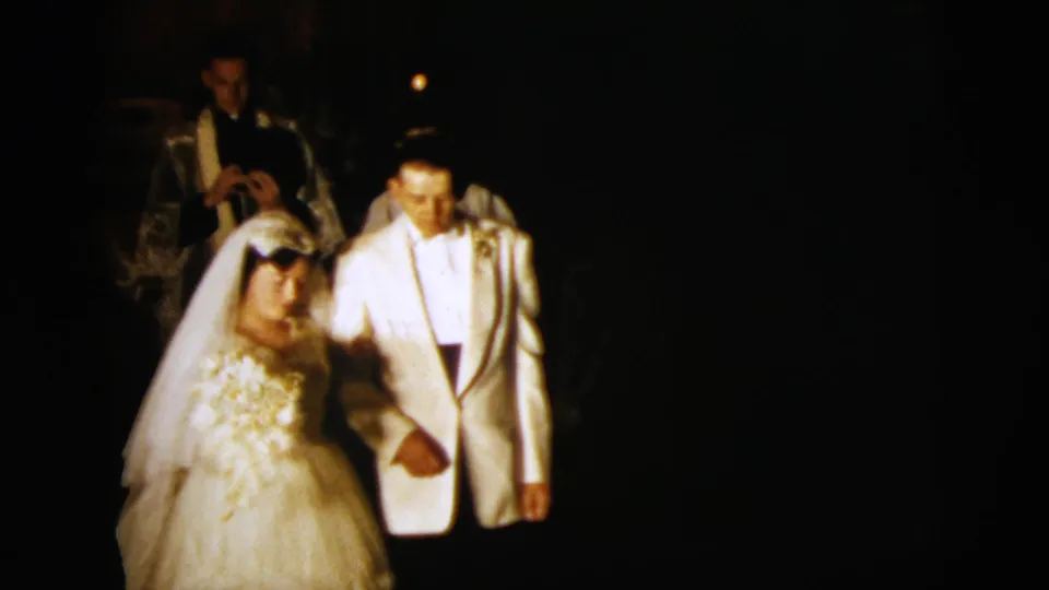 The bride and groom kneel together near the altar during the 1958 New York City wedding ceremony, with a vested figure behind them.