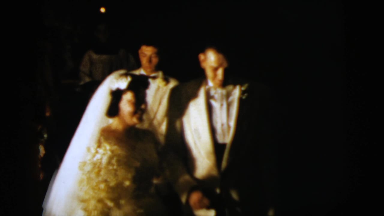 Bride and groom appear with male wedding-party members in a dimly lit 1958 New York City home-movie scene.