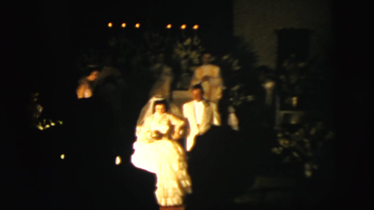 Bride and groom stand near the church aisle with guests and altar details in shadow.