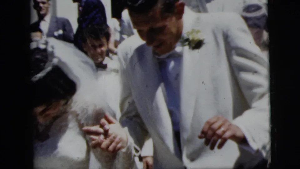 The bride and groom appear hand in hand in a 1958 New York City wedding crowd, with rice visible near their clothing.