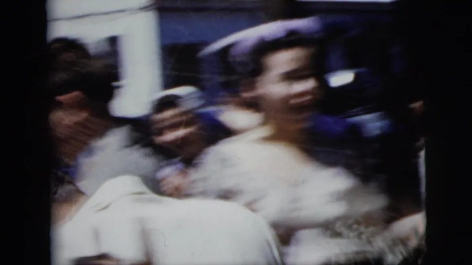 The bride and surrounding guests blur past the handheld camera in a 1958 New York City wedding exit scene.