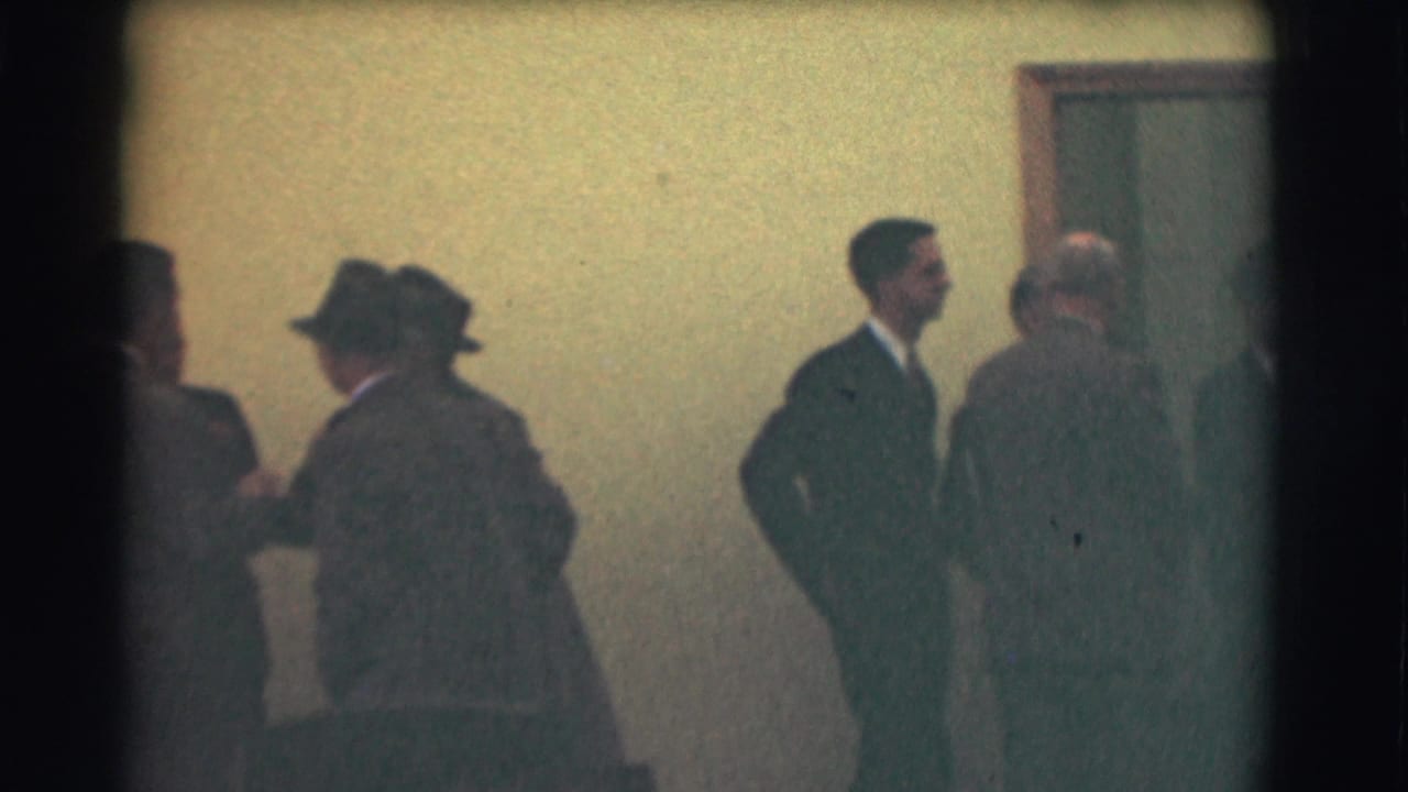 The final frame shows suited men dispersed in the 1959 Saint Louis interior, one near the right side and others partly obscured.