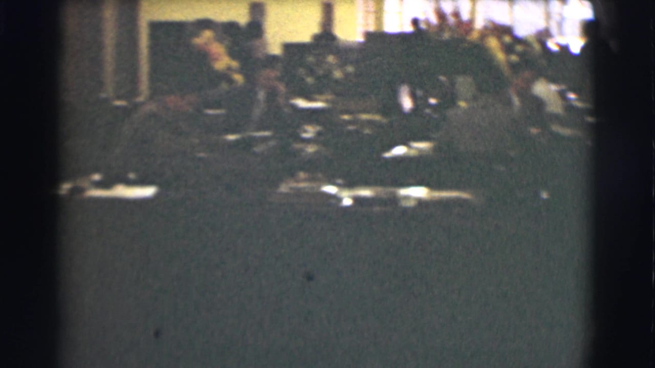 1959 Saint Louis office scene with adults working at desks amid papers and period office equipment, seen in soft 8mm color.