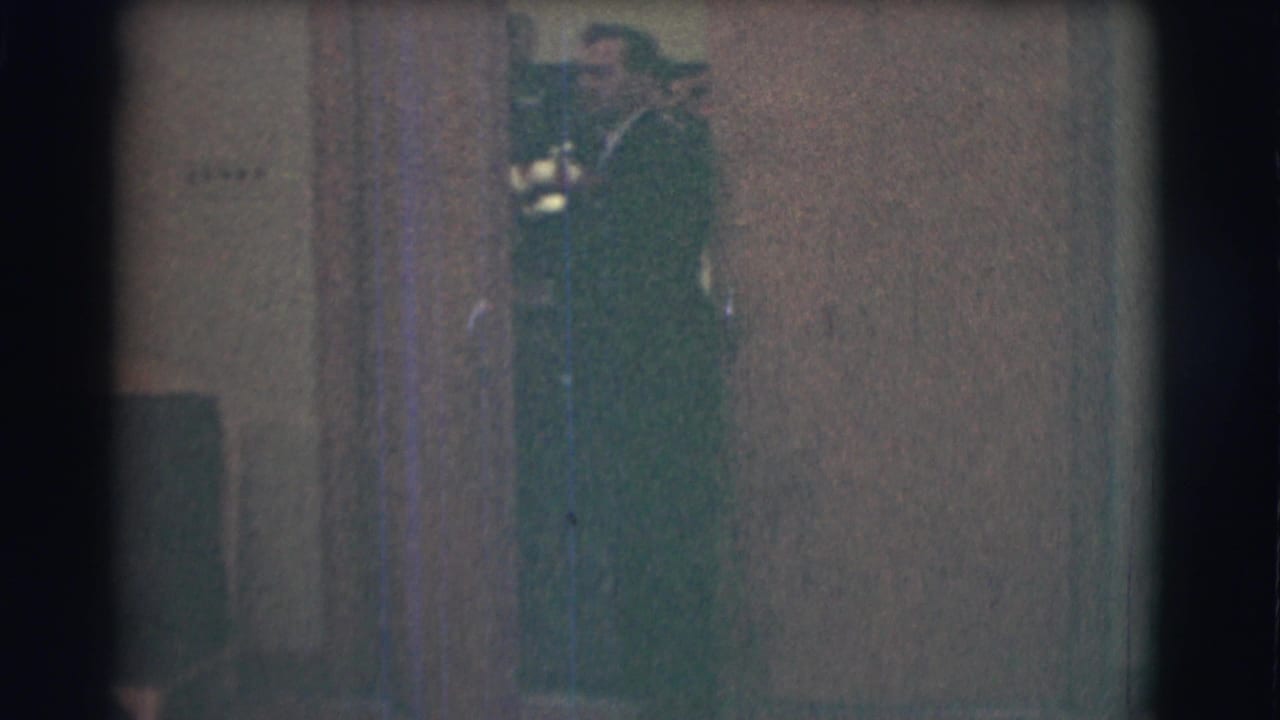 1959 Saint Louis home-movie frame showing a suited man partly obscured near an interior doorway.
