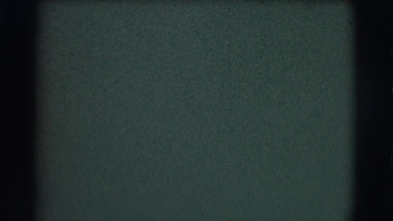 Soft, mostly abstract 8mm frame with dark borders and a greenish blurred field before the church interior action appears.
