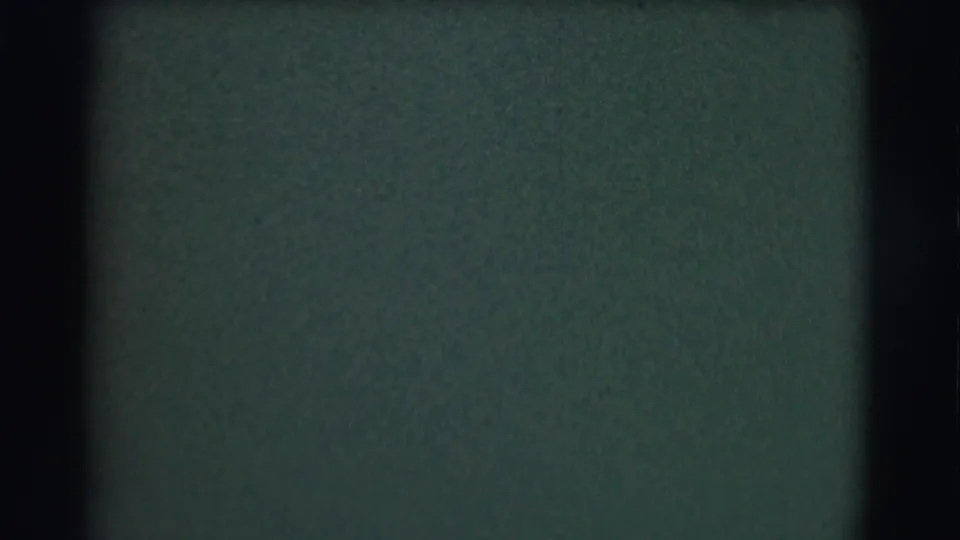 Soft, mostly abstract 8mm frame with dark borders and a greenish blurred field before the church interior action appears.