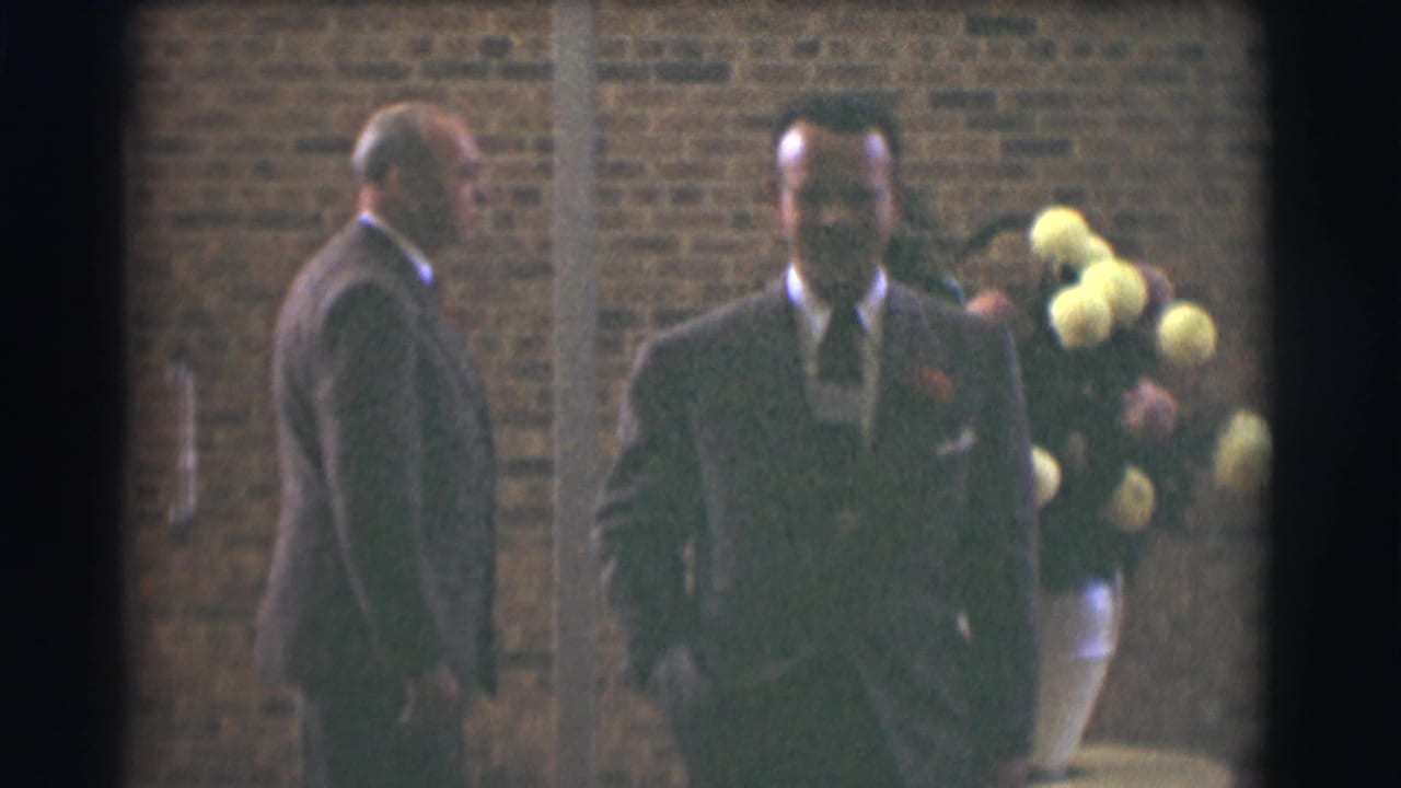 Two well-dressed men in suits appear outside a brick building in Saint Louis, Missouri, in 1959 home-movie footage.