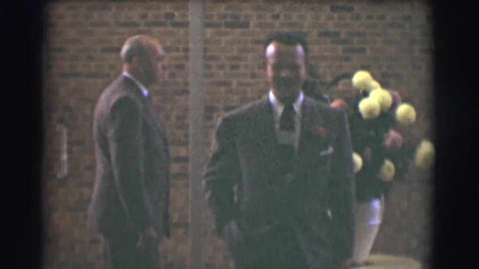 Two well-dressed men in suits appear outside a brick building in Saint Louis, Missouri, in 1959 home-movie footage.