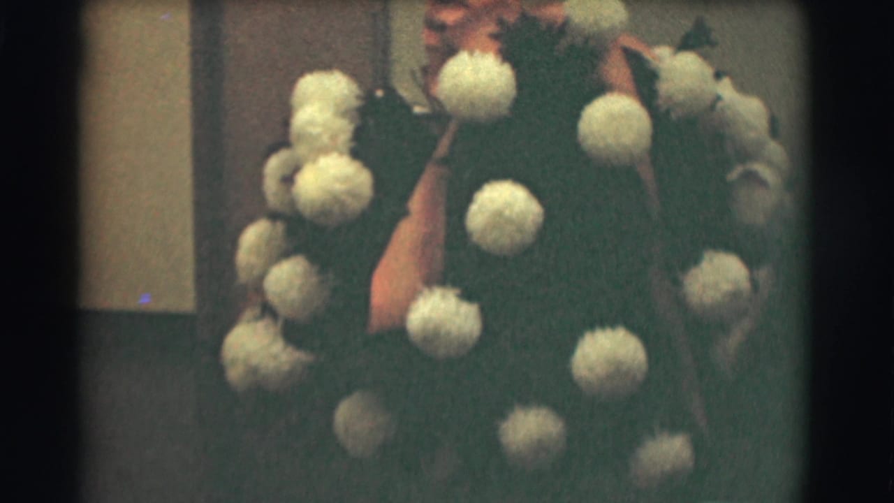 A man in a dark suit and tie appears beside a large pale floral arrangement in this 1959 Saint Louis home-movie frame.