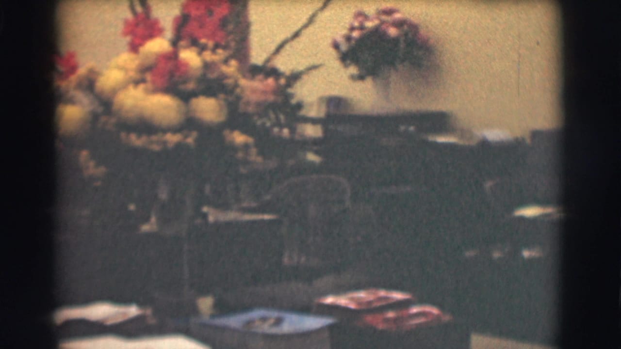 Large yellow and red flower arrangement on a desk in a dim office interior.