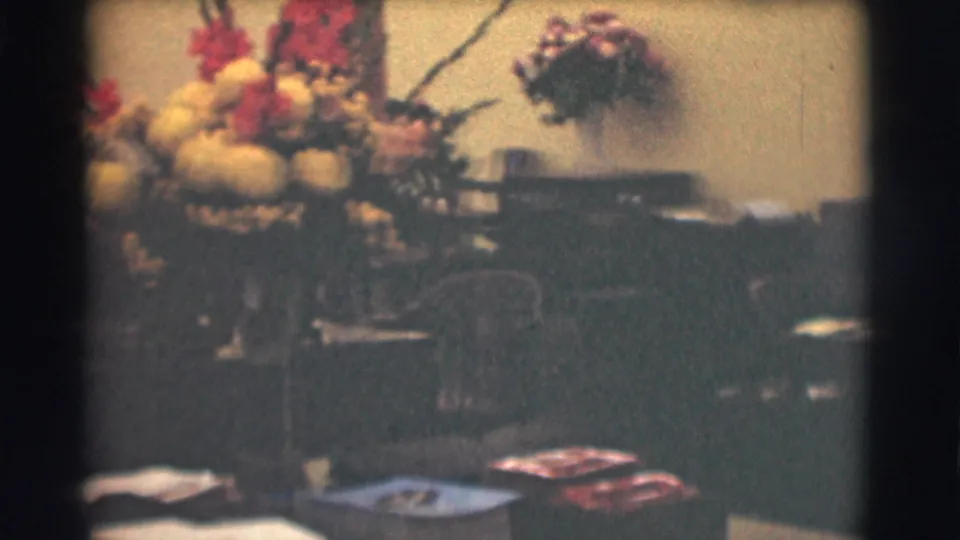 A flower arrangement sits prominently on a desk in a 1959 Saint Louis office interior, with chairs and paperwork in soft focus.