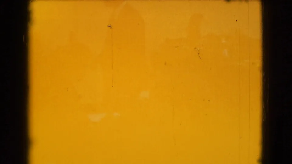 A warm orange 8mm frame shows mostly exposed film surface with only faint interior traces and film marks visible.