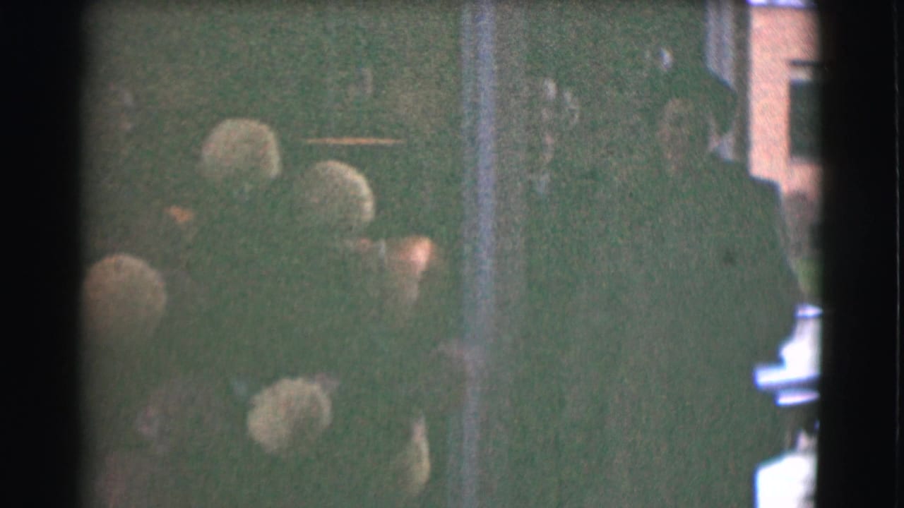People in winter coats gather near a dim doorway with a building visible beyond.