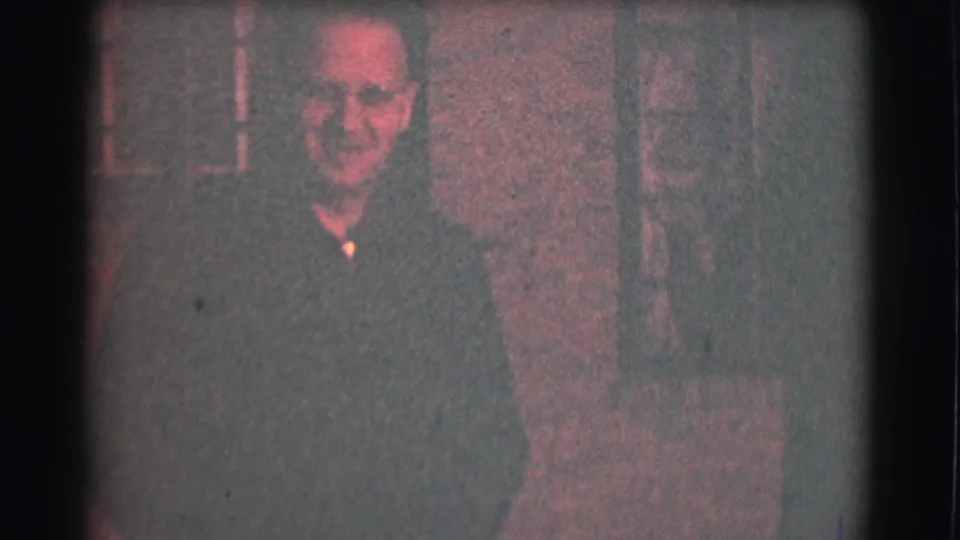 Smiling adult man in glasses moves nearer to the camera in the 1959 Saint Louis home-movie scene.