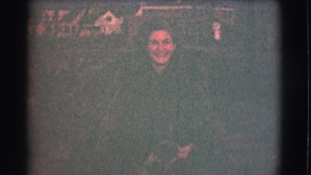 A smiling woman appears in a Saint Louis night scene from 1959, framed closely against a dark, grainy residential-looking background.