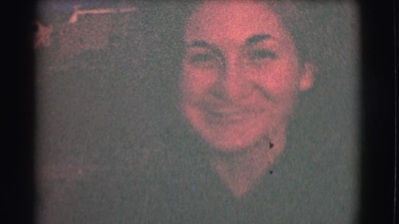 Smiling woman framed from the shoulders up on grainy 8mm film.